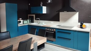 Una cocina moderna con armarios azules, una mesa de comedor de madera y sillas negras.