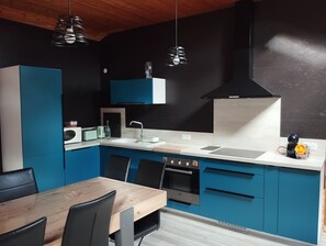 A modern kitchen with blue cabinets, a wooden dining table, and black chairs. - La Canissa Carrada Vacation Rental for 12 to 14 People  (Chaspuzac)