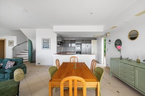 Une cuisine moderne avec un îlot central, un coin repas avec une table et des chaises en bois, et un canapé vert.