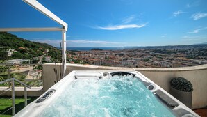 Un bain à remous avec vue sur la ville, une rambarde en métal et un ciel dégagé.