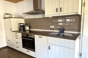 Eine kleine Küche mit wei ßen Schränken, einer Edelstahl-Spüle und einem eingebauten Backofen.