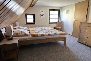 A bedroom with a wooden bed, a chair, a dresser, and two windows. - Holiday home in Lübbenau with swimming pool (Lübbenau)