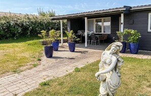 Ein Haus mit Terrasse, Gartenmöbeln und Blumentöpfen.