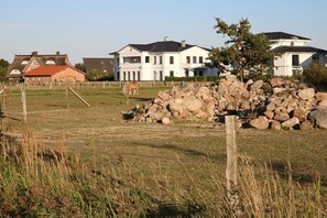 Ländliche Landschaft mit einem großen Steinhaufen, einem Holzzaun und mehreren Häusern im Hintergrund.
