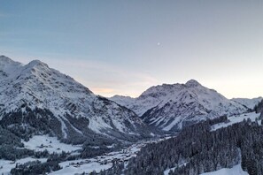 A mountainous landscape with snow-covered peaks and a valley with a small settlement. - Holiday apartment in Hirschegg with balcony (Hirschegg)