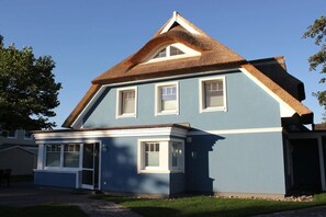 Ein zweistöckiges Haus mit einem steilen Satteldach, einer Veranda und einer Garage.