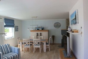 Ein Essbereich mit Holztisch und -stühlen, einer Wanduhr und einem Kamin.