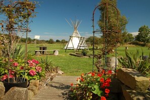 A garden with a wooden pathway, a white teepee, and various plants. - Holiday apartment with 5 bedrooms (Kellenhusen)