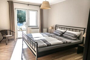 A bedroom with a bed, a chair, a lamp, and a window. - Holiday apartment with 5 bedrooms (Kellenhusen)