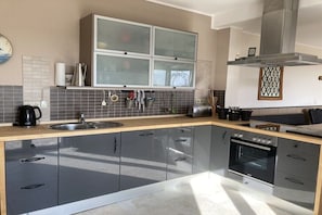 A modern kitchen with a large island, stainless steel appliances, and a tiled backsplash. - Holiday apartment with 5 bedrooms (Kellenhusen)