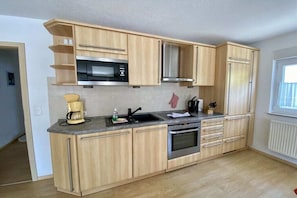 Eine moderne Küche mit Holzausstattung, integriertem Mikrowellenherd, Backofen und Spüle.
