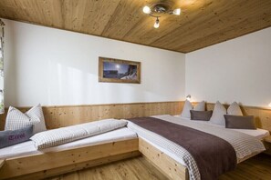 A room with wooden ceiling and walls, a bed with checkered bedding, a bench, and a framed picture on the wall. - Spitaler holiday apartment (Hippach)