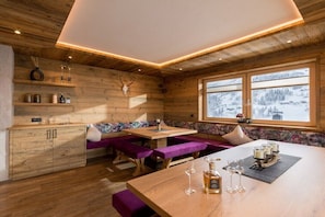 A wooden interior with a wooden table, benches, and a window with a snowy view. - Spitaler holiday apartment (Hippach)