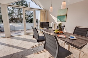 Ein Essbereich mit Tisch, Stühlen, einem Fernseher und Blick durch große Glaswände.