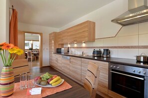 Eine moderne Küche mit Holzausstattung, einem Edelstahlherd und einer Obstschale auf der Arbeitsfläche.