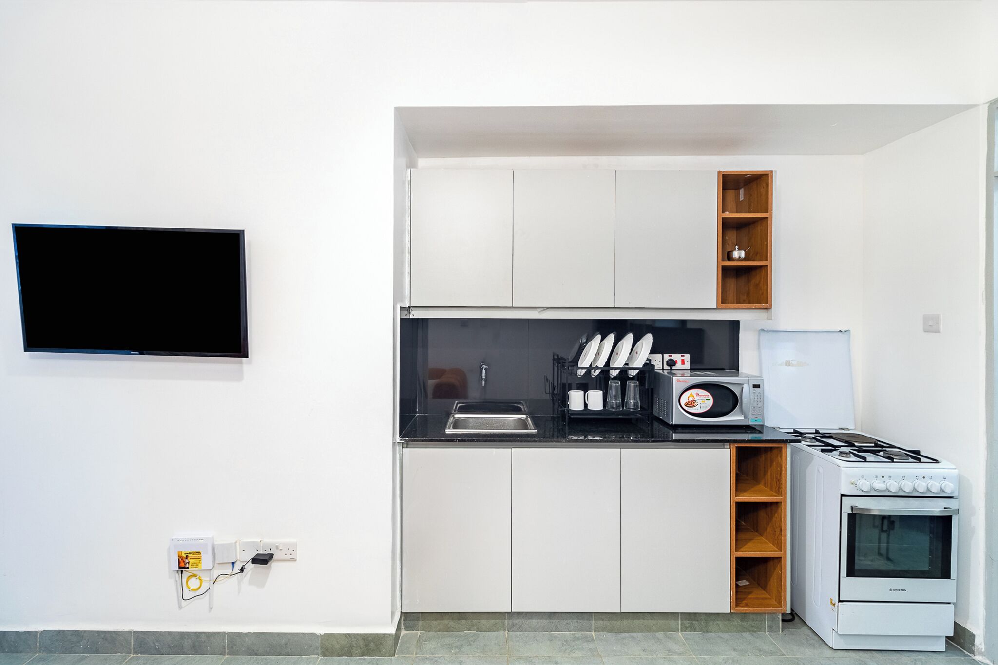 A compact kitchen with a flat-screen TV, a microwave, a stove, and a sink.