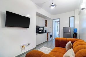 Eine moderne Küche mit Flachbildfernseher, Wasserspender und Kühlschrank.