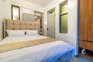 Ein Schlafzimmer mit einem großen Bett, einem Kleiderschrank und einer Tür mit Frostglasfenster.