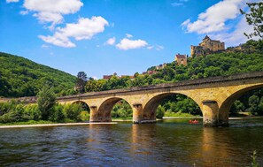 Eine Stegenbrücke über einem Fluss, im Hintergrund ein Schloss auf einem Hügel.