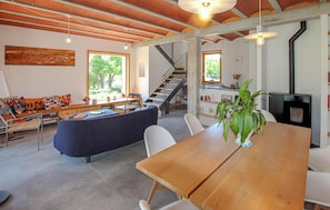 A spacious living area with a wooden dining table, a sofa, and a staircase leading to another level. - Bastide Néo Provencale (Grignan)