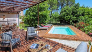 A wooden deck with a hot tub, lounge chairs, and a table with a magazine and decorative items. - Bastide Néo Provencale (Grignan)