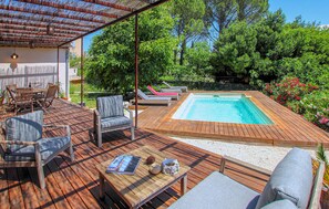A wooden deck with a hot tub, lounge chairs, and a table with a magazine and decorative items. - Bastide Néo Provencale (Grignan)