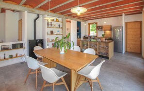 A modern kitchen with a wooden table and chairs, a refrigerator, and a plant. - Bastide Néo Provencale (Grignan)