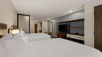 Ein Hotelzimmer mit zwei Betten, einem Fernseher, einem Schreibtisch und einem Kleiderschrank.