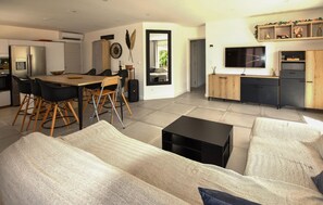 A modern living room with a sofa, a coffee table, and a dining area with chairs and a table. - Gorgeous home in Mérindol (Mérindol)