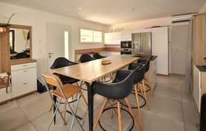 A modern kitchen with a dining table and chairs, a refrigerator, and a microwave. - Gorgeous home in Mérindol (Mérindol)