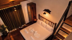 Un letto rifatto con asciugamani, una testiera in legno, una lampada a parete e una scala.