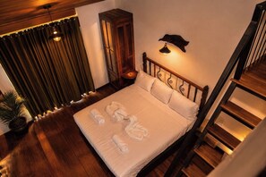 Un lit bien fait, avec des serviettes, une tête de lit en bois, une lampe fixée au mur et un escalier.