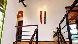 Una scala con gradini in legno e ringhiere in metallo che conduce a una stanza con una parete bianca e una pianta.