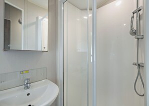 Ein Badezimmer mit einem weißen Waschbecken, einem Spiegel und einer Duschkabine.