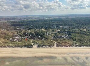 Eine Küstenlandschaft mit Strand, verstreuten Häusern und hügeligem Gelände.