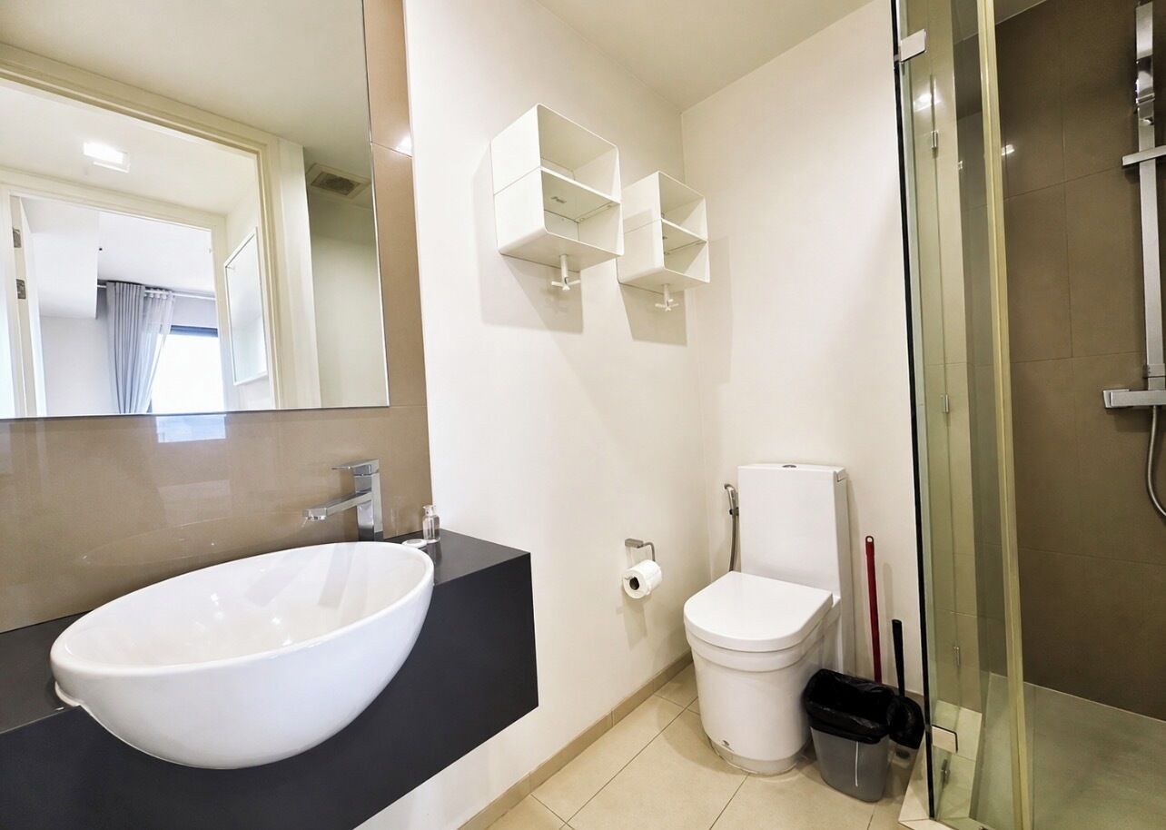 Ein modernes Badezimmer mit einem großen, weißen Waschbecken, einer Toilette und einer Duschkabine aus Glas.