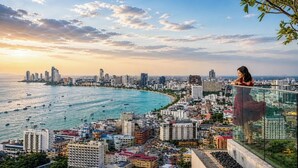 A cityscape with a high-rise building overlooking a coastal area with boats. - 1 BR Sea View Condo Near Walking Street (ตำบล หนองปรือ)