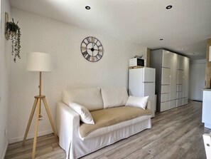 Ein Wohnzimmer mit einer Couch, einer Stehlampe, einer Uhr und einem Kleiderschrank.