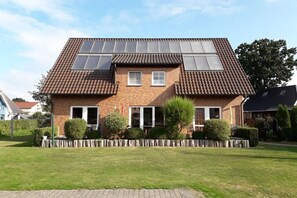 Ein zweistöckiges Haus mit Ziegeldach, Solaranlage und einem gepflegten Rasen.