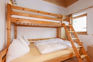 A bunk bed with a wooden ladder, white bedding, and a window with a view. - Holiday home with 1 bedroom (Fieberbrunn)