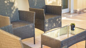 Wicker meubilair met een glazen tafel, een deur en betegelde vloer.