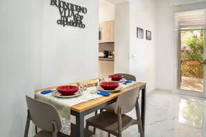 A dining area with a table set for four, chairs, a kitchen visible through an open door, and a sign on the wall. - BorgoNaro, an authentic oasis of peace located in the charming village of Dattilo. (Dattilo)