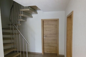Eine Treppe mit Metallgeländern und Holzstufen, eine Holztür und eine schlichte Wand.
