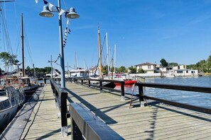 Eine hölzerne Pier mit angebundenen Booten, einem klaren Himmel und Gebäuden im Hintergrund.