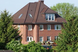 Ein zweistöckiges Backsteinhäuschen mit geneigtem Dach, mehreren Fenstern und einer sichtbaren Garage.
