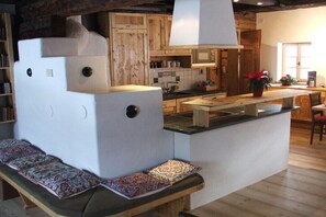 Eine gemütliche Küche mit Holzausbau, einer zentralen Kochinsel und einer Bank mit gemusterten Kissen.