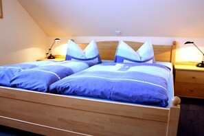 Ein Doppelbett mit Holz-Kopfteil, zwei Nachttische mit Lampen und eine kleine Schublade.