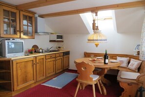 Eine Küche mit Holzausstattung, einer Mikrowelle, einem Spülbecken, einem Esstisch mit Stühlen und einer Pendelleuchte.