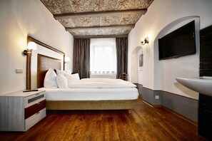 Ein Schlafzimmer mit einem großen Bett, einem Fernseher, einem Nachttisch aus Holz und einer dekorativen Decke.