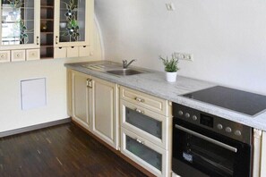 Eine Küche mit Spüle, Herd und Backofen, Holzschränken und einem Blumentopf.